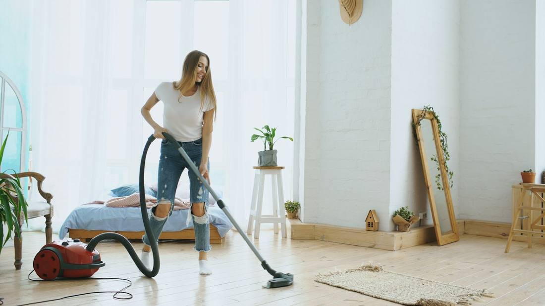 Femeie care aspiră într-o sufragerie luminoasă